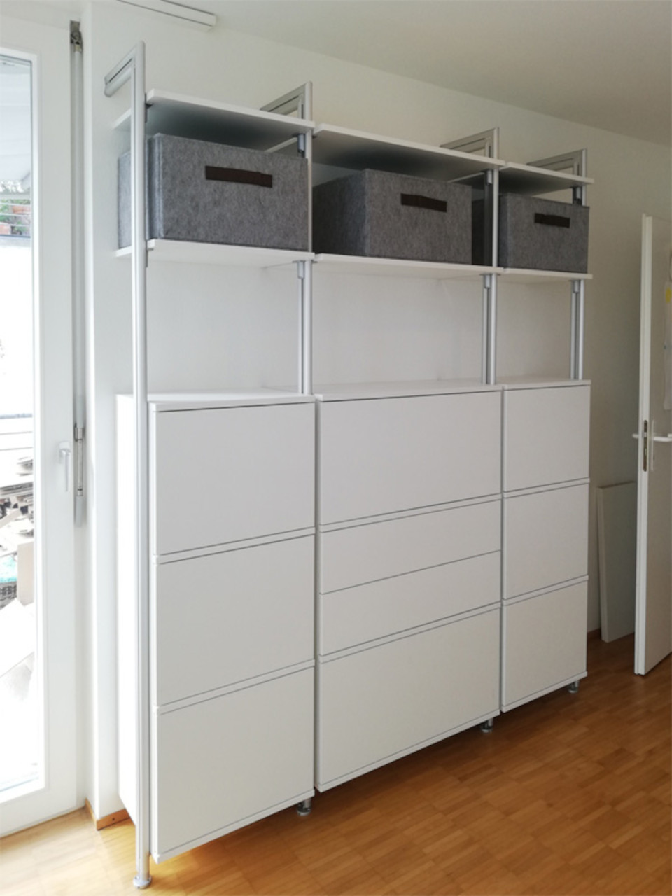 Kundenfoto begehbares Schranksystem mit viel Stauraum, kleine Tiefe Kundenfoto begehbares Schranksystem mit weißen Fronten, offenen Regalen und Aufbewahrungsboxen – moderne Lösung für funktionalen Stauraum
